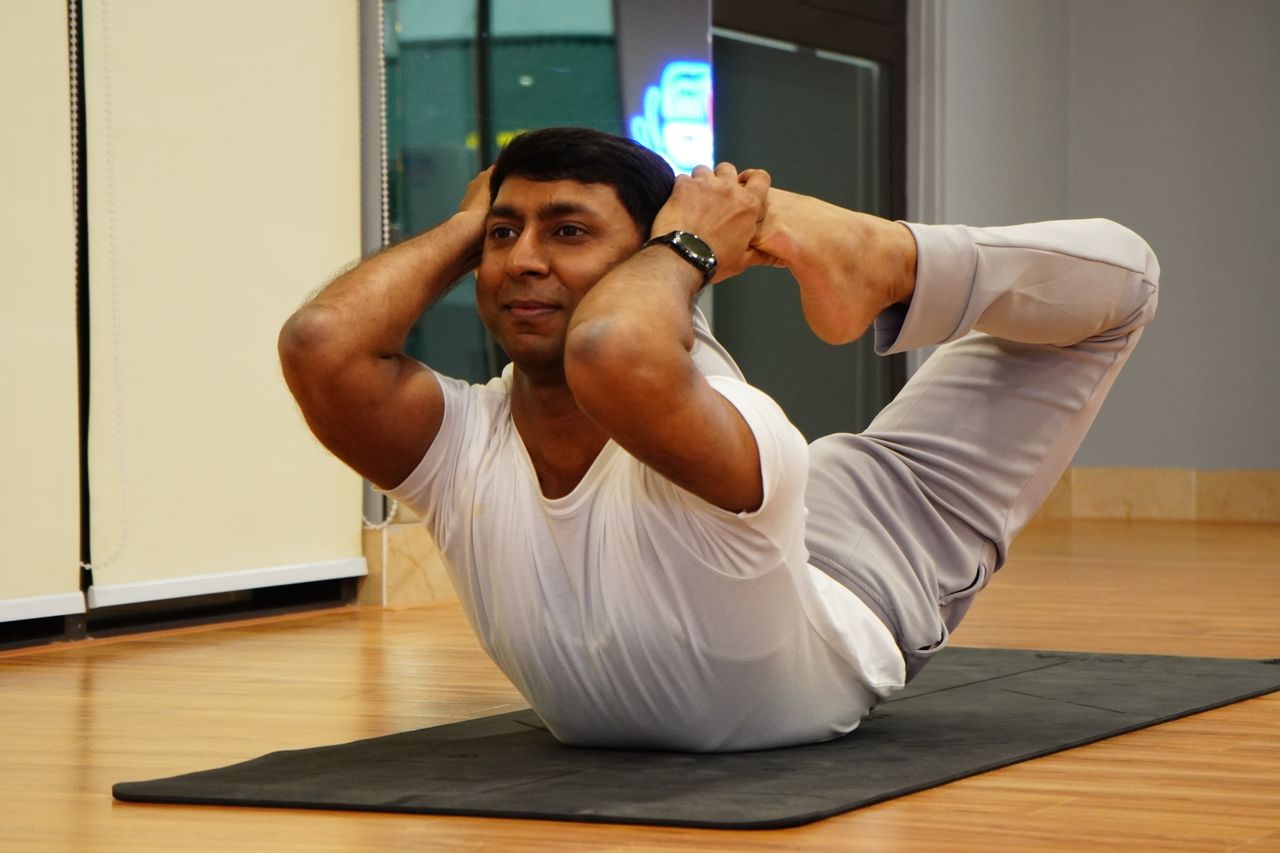 Adult male performing stretching exercise indoors on a yoga mat showing flexibility.